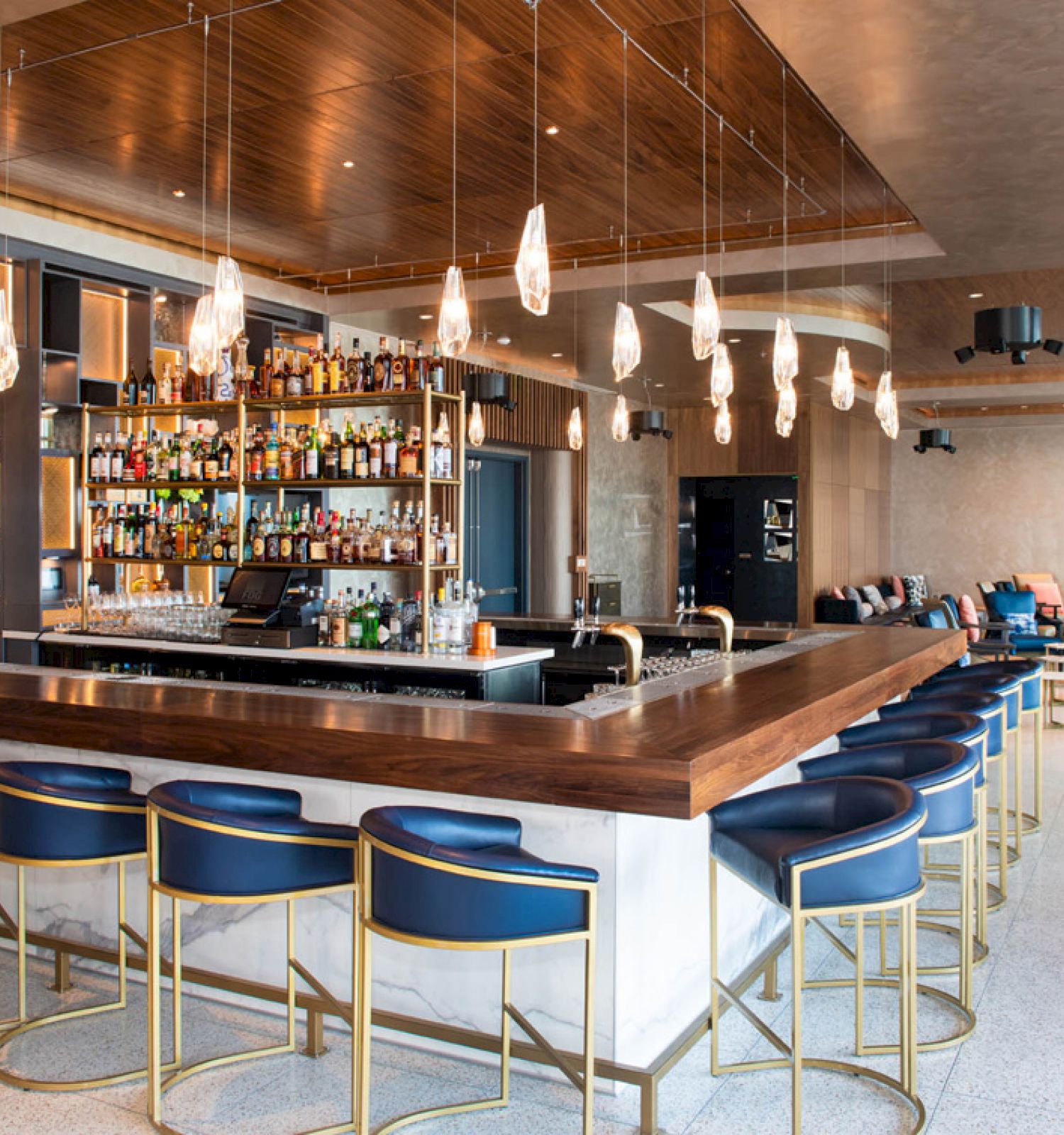 The image shows a modern bar with stylish seating, a well-stocked back bar, and pendant lighting, creating an inviting atmosphere.