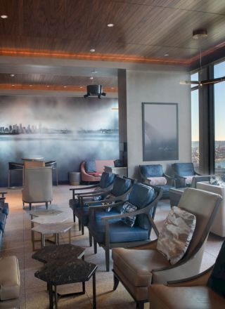 A modern lounge area with comfortable seating, large windows offering a scenic view, and stylish decor on the walls.