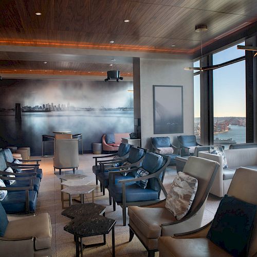 A modern lounge area with comfortable seating, large windows offering a scenic view, and a city skyline mural on the wall ends the sentence.