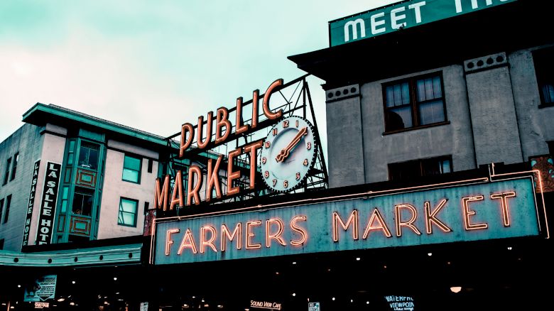 A vibrant sign reading "Public Market" and "Farmers Market" with a large clock is displayed on a building.